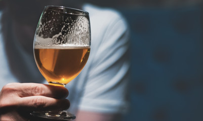 man holds a glass of beer in his hand at the bar or pub