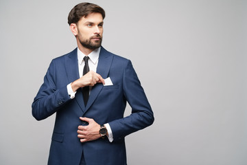 studio photo of young handsome businessman wearing suit holding business card