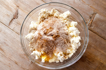 Raw mixture for making cottage cheese cakes in glass bowl on old wooden background