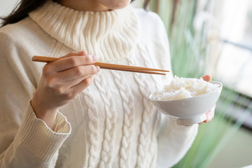 茶碗に盛られた白米と箸を持つ女性の手元