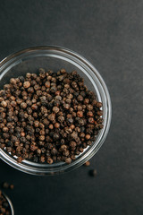 Spices on black background. Black pepper in a bowl.