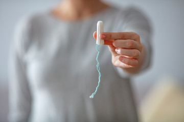 Close up of a woman's hands which are holding a tampon. Tampo on womans hand before intravaginal aplication. Woman holds a tampon in toilet. Woman holds a tampon sitting in a toilet - obrazy, fototapety, plakaty