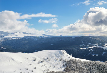 Fototapeta na wymiar A beautiful viewpoint of the snowy volcanic mountain range during the winter, in Auvergne.