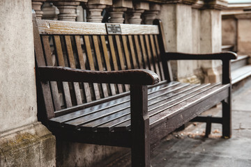 Fototapeta na wymiar lonely dark brown wooden bench in a london street