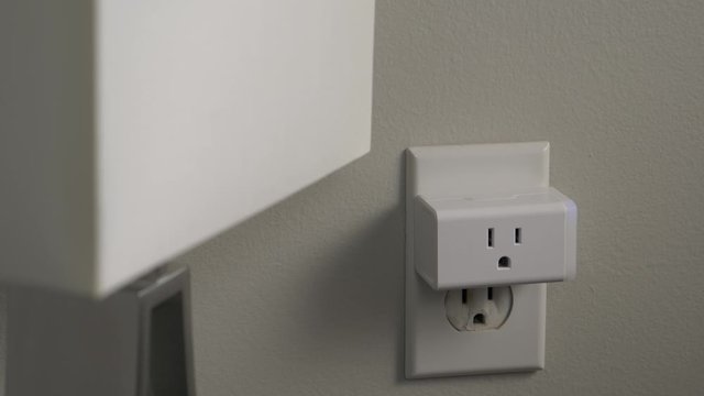 Connecting a WiFi smart plug into a house outlet to control a lamp light bulb with the wireless network.