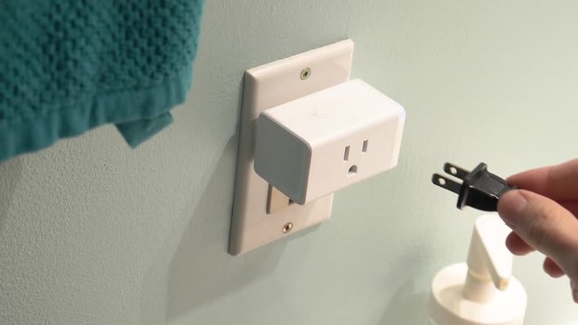 Connecting a WiFi smart plug into a bathroom outlet to control an electrical device with the wireless network.