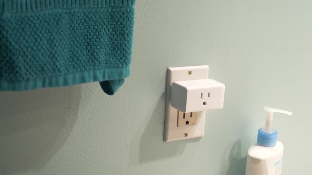 Connecting a WiFi smart plug into a bathroom outlet to control an electrical device with the wireless network.