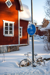 White bike in the snow in front of a red swedish house