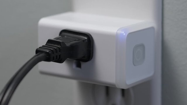 Connecting a WiFi smart plug into a house outlet to control a lamp light bulb with the wireless network.