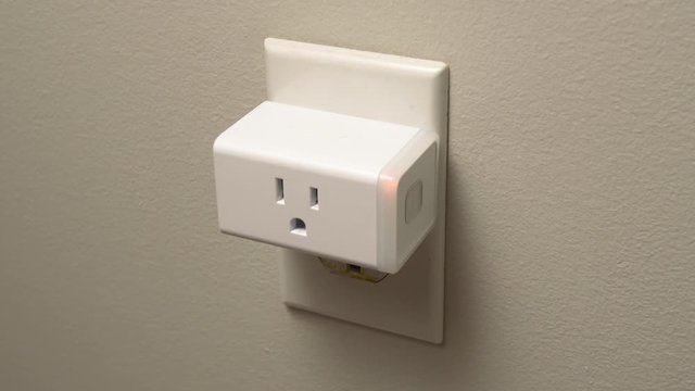 Connecting a WiFi smart plug into a house outlet to control a lamp light bulb with the wireless network.