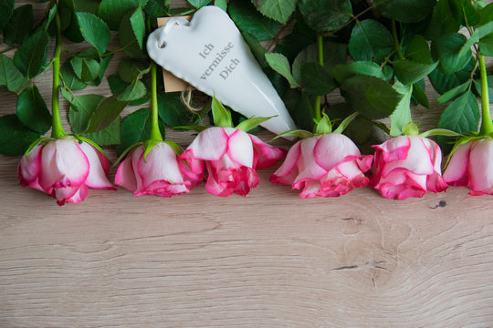 Porcelain white heart with pink roses on the wood table.