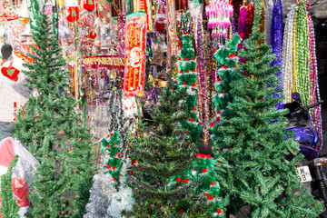 Fototapeta na wymiar New year fair,Big sale of Christmas trees and Santa doll. Sale of artificial fir trees and festive decorations in tents