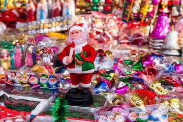 Fototapeta na wymiar New year fair, Big sale of Christmas trees and Santa doll. Sale of artificial fir trees and festive decorations in tents. Merry Christmas and Happy New Year 2020.