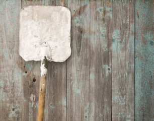 A large metal snow shovel stands against the wall
