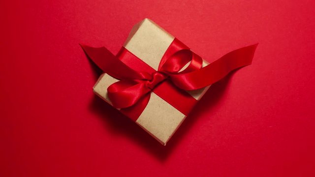 Gift box with a red ribbon bow on red background. Flat lay top view stop motion animation 