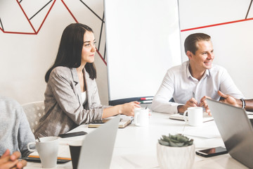 A team of young office workers, businessmen with laptop working at the table, communicating together in an office. Corporate businessteam and manager in a meeting. coworking.