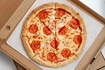Pepperoni pizza in a cardboard box on a white background - top view