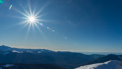 Rosa Khutor ski resort. Mountain landscape of Krasnaya Polyana and sun shining, Sochi, Russia.