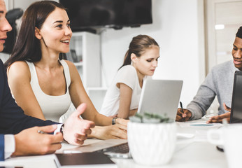 A team of young office workers, businessmen with laptop working at the table, communicating together in an office. Corporate businessteam and manager in a meeting. coworking.