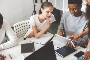 A team of young office workers, businessmen with laptop working at the table, communicating together in an office. Corporate businessteam and manager in a meeting. coworking.