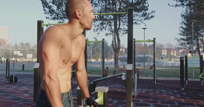 Young shirtless muscular man standing in fitness park