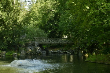 Fototapeta na wymiar Le pont rustique en rocaille sous la végétation très dense au parc Josaphat à Schaerbeek