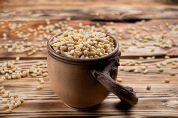 pine nuts in a beautiful decorative cup on pine boards close-up