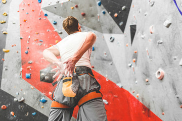 Sportsman climber is looking on steep rock, climbing on artificial wall indoors. Extreme sports and bouldering concept