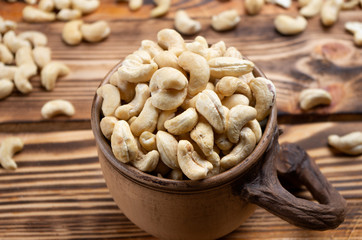 cashew nuts in a decorative cup on wooden boards close-up