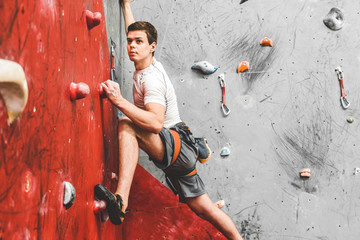 Sportsman climber moving up on steep rock, climbing on artificial wall indoors. Extreme sports and bouldering concept © xartproduction