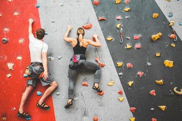 couple of athletes climber moving up on steep rock, climbing on artificial wall indoors. Extreme...