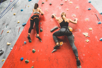 Athletes climber moving up on steep rock, climbing on artificial wall indoors. Extreme sports and...