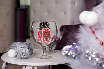 Handmade Christmas toys on a white coffee table. Christmas beautiful composition as an option to create a festive mood. Red flashlight and a ball of silver thread. On the table is a vase in the form o