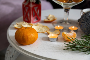 Christmas candles and tangerines on the table against the background of New Year's decor. Christmas association.