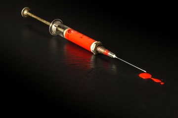 Syringe and blood on black background. Risk of HIV infection. Flu vaccination. Blood test. Old...