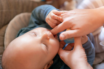 Searching for the first babies tooth. Mother tries to sooth teething pain. Close up, selective focus.