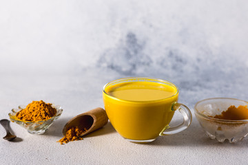 Golden turmeric milk on the white background with spices cinnamon and ingredients