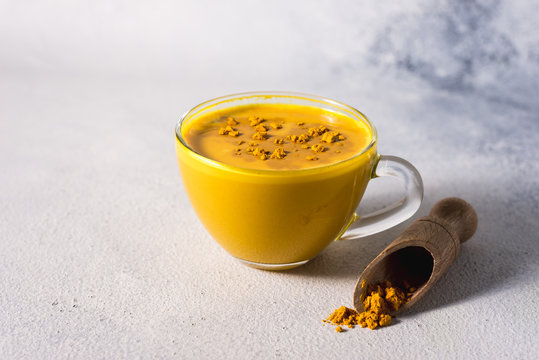 Golden turmeric milk on the white background with spices cinnamon and ingredients
