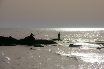 Fisher man at the sea during sunset silhouette