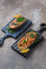 Two salmon steaks with vegetables on wooden boards, copy space
