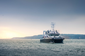 Commercial vessel goes to sea in cloudy weather. rays of the sun break through
