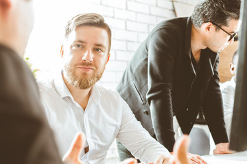 A team of young businessmen working and communicating together in an office. Corporate businessteam and manager in a meeting.