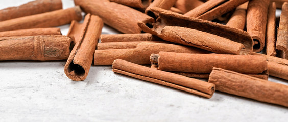 Heap of cinnamon bark sticks on white stone like board - space for text left down corner