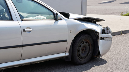 Crashed car standing on road next to curb, side view with demolished front and used airbag inside...