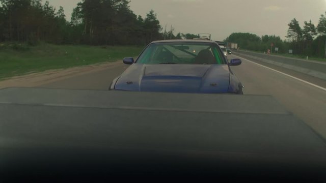 Transportation of a sports car on a highway. View from a towing vehicle.