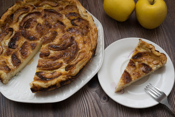 piece of apple pie near the cake and some apples on a wooden background