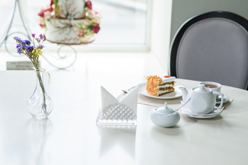 Delicious carrot cake and a cup of black tea on the table in a cozy coffee shop