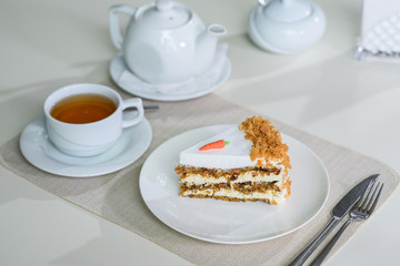 Delicious carrot cake and a cup of black tea on the table in a cozy coffee shop