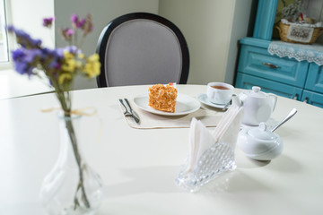 Delicious carrot cake and a cup of black tea on the table in a cozy coffee shop