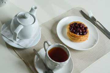 Danish with cherries and black tea on a table in a cozy coffee shop